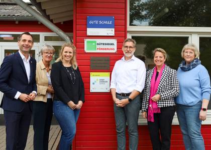 Die Gruppe steht vor der Plakette an der Grundschule