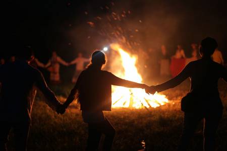 Menschen tanzen um ein großes Feuer