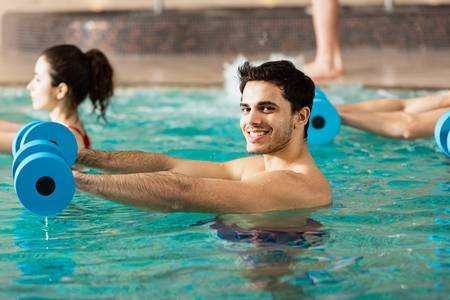 Ein Mann in einem Wassergymnastik-Kurs blickt freundlich in die Kamera