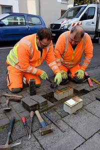 Mitarbeiter des Bauhofes verlegen die Stolpersteine.