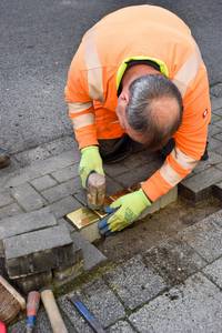 Ein Mitarbeiter des Bauhofes befestigt die Stolpersteine.