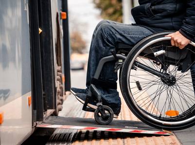 Rollstuhlfahrer fährt auf Rampe in einen Bus