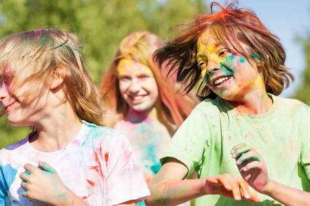 3 Kinder, die auf einem Holi-Fest mit farbigem Pulver beschmiert sind