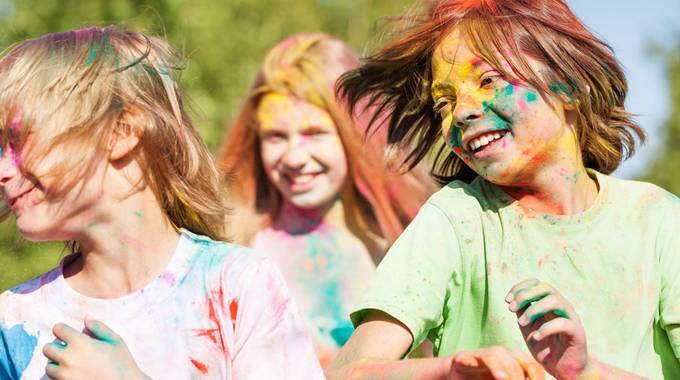 3 Kinder, die auf einem Holi-Fest mit farbigem Pulver beschmiert sind