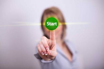 Eine Frau drückt mit ihrem Finger einen grünen Button mit der Aufschrift "Start"