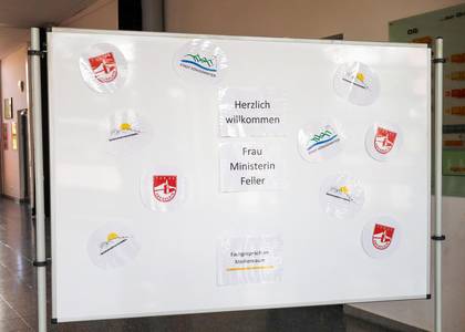 Tafel mit Logos der Veranstaltenden und Willkommensgrüße für die Ministerin