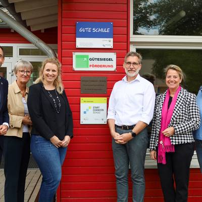 Die Gruppe steht vor der Plakette an der Grundschule