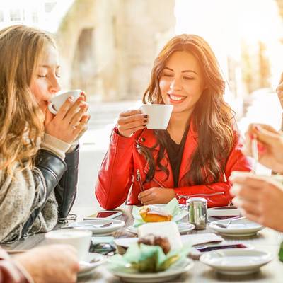 3 Frauen und Ein Mann sitzen am Tisch und trinken Kaffee