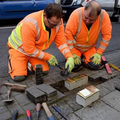 Mitarbeiter des Bauhofes verlegen die Stolpersteine.