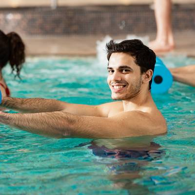 Ein Mann in einem Wassergymnastik-Kurs blickt freundlich in die Kamera