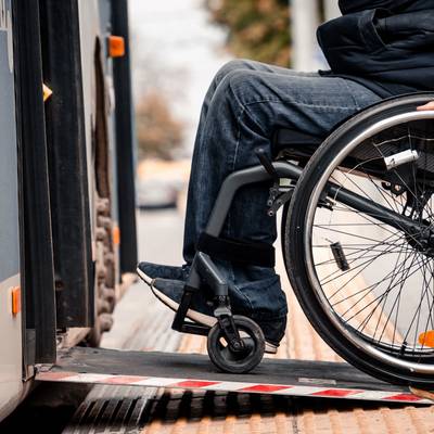 Rollstuhlfahrer fährt auf Rampe in einen Bus