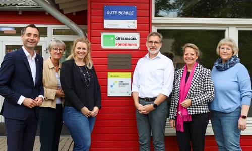 Die Gruppe steht vor der Plakette an der Grundschule