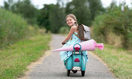 Schulkind auf einem Roller mit Schultüte