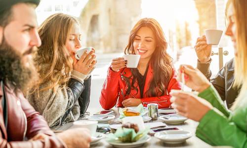 3 Frauen und Ein Mann sitzen am Tisch und trinken Kaffee