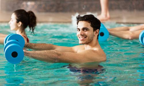 Ein Mann in einem Wassergymnastik-Kurs blickt freundlich in die Kamera