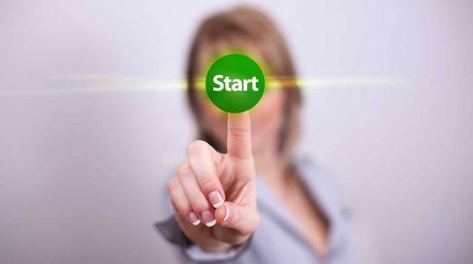 Eine Frau drückt mit ihrem Finger einen grünen Button mit der Aufschrift "Start"