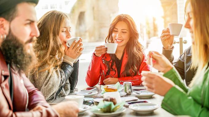 3 Frauen und Ein Mann sitzen am Tisch und trinken Kaffee