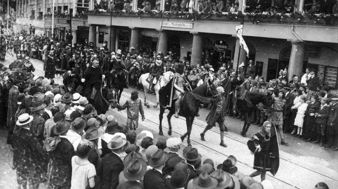 schwarz-Weiß-Foto eines Festzuges mit Pferden