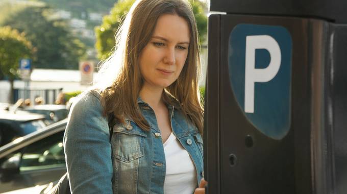 Eine Frau steht vor einem Parkautomaten